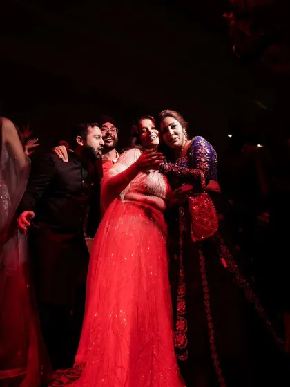 A candid moment under the red lights of the dance floor. The lighting creates a vibrant and energetic mood for this group photo.