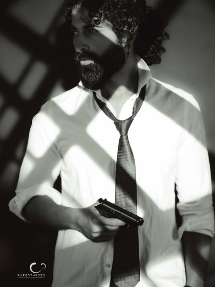 A powerful and mysterious portrait. The high-contrast black and white emphasizes the dramatic lighting and his strong, silent presence.