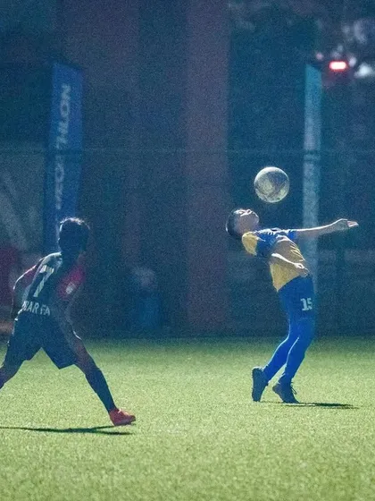 A player attempts a header to clear the ball during the Thane Youth League U13 semi-final.