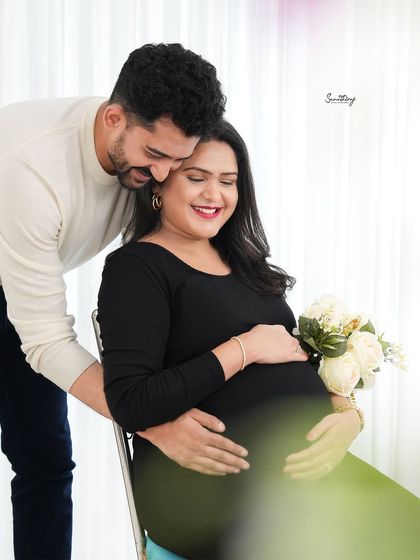 A tender moment between a couple in a bright, high-key setting. The husband's gentle embrace and the wife's serene expression create a beautiful and loving portrait.