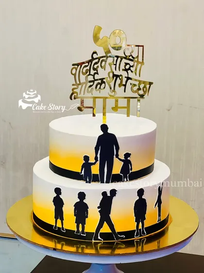 A special two-tier cake for a 'Mama' (uncle's) 50th birthday. The design features silhouettes of a father and children, with a 'Vadhdivsachya Hardik Shubhechha' topper in Marathi.