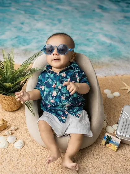 Too cool for the studio. This three-month-old is chilling in his very own beach setup, complete with sand, shells, and a tiny suitcase.