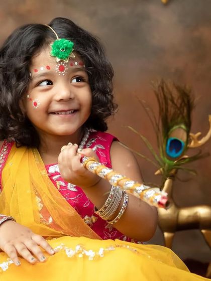 A bright and happy portrait of our little Radha, smiling with a peacock feather flute.