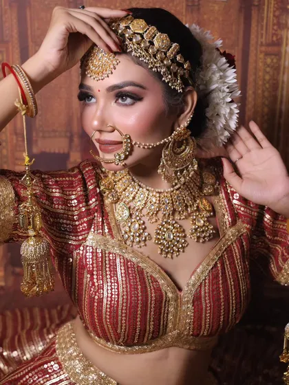 A full shot of the bride in a red and gold lehenga, showcasing the entire golden jewellery set, including the kalire.
