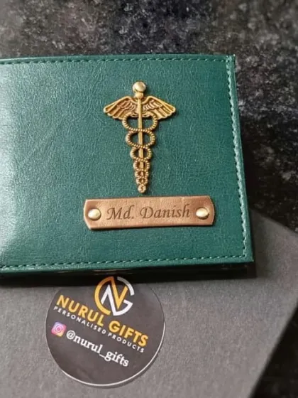 This green personalized wallet with a caduceus charm is a perfect gift for a doctor. The name 'Md. Danish' is engraved on the metal plate.