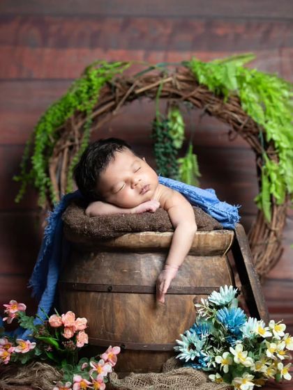 Another angle of the newborn on the barrel, this time with a wreath of greenery in the background.