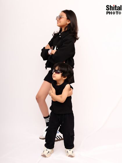 Built-in best friends with a bit of attitude. This fun sibling portrait showcases their personalities with matching outfits and cool poses.