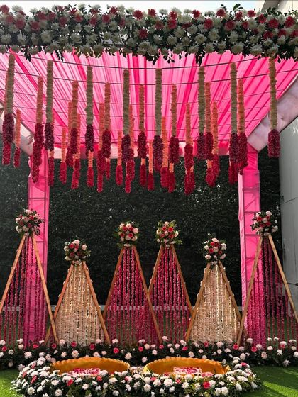 A detailed shot of our pink Haldi mandap, showing the hanging floral tassels and the intricate flower arrangements on the triangular back panels.