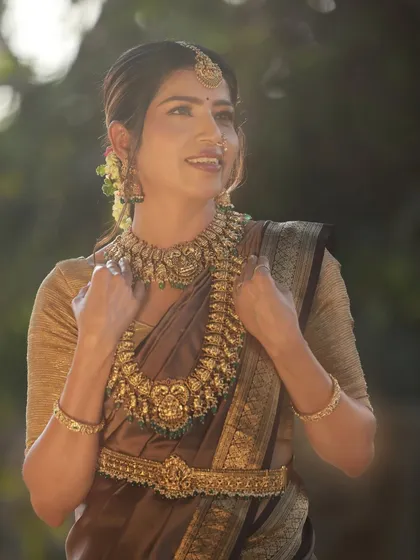 An outdoor portrait with beautiful backlighting from the sun. This creates a soft, ethereal glow around the model, enhancing the beauty of the traditional bridal look.