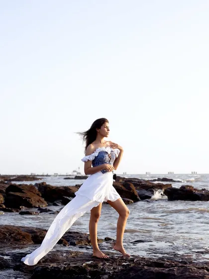 A wide shot that places the model in the rugged, beautiful landscape of a rocky beach, creating a sense of freedom and adventure.