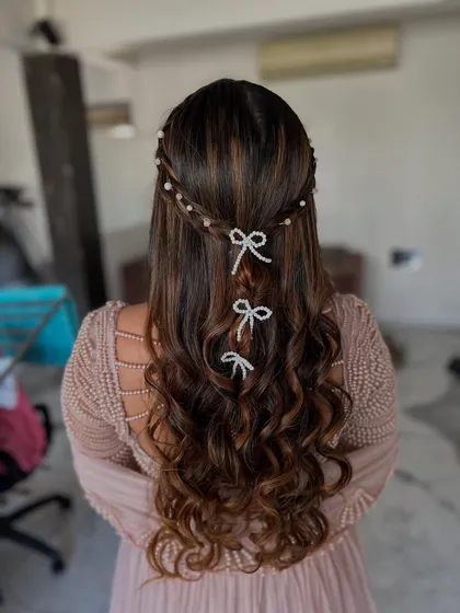 A fun and trendy hairstyle featuring soft waves and adorable pearl bow accessories. This is a great choice for a younger client or anyone looking for a playful touch.