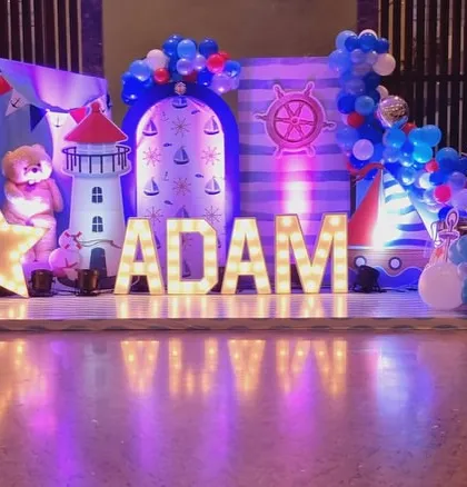 The main stage for a sailor-themed birthday, with marquee letters spelling the birthday boy's name and nautical props like a lighthouse and anchor.