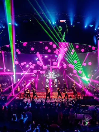 A wide shot of a spectacular sangeet performance. The lasers, lights, and dancers create a high-energy, concert-like atmosphere that we love to capture in all its glory.
