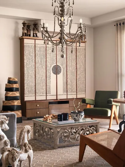 A close-up of the living area, highlighting the carved wooden coffee table and the custom-designed cabinet. Each piece was chosen for its unique character and craftsmanship, contributing to the home's soulful feel.