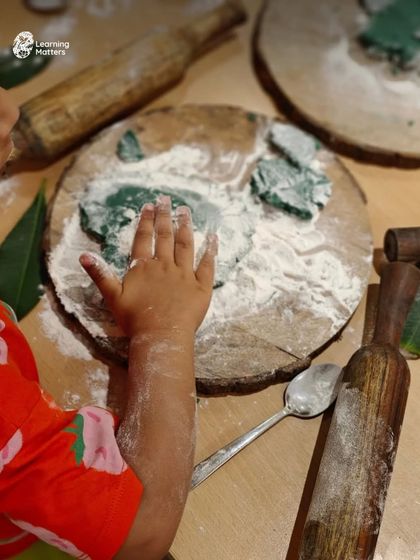 Kneading, rolling, and pressing playdough are powerful exercises for little hands. Here, a child explores textures and shapes, building fine motor strength, finger dexterity, and hand-eye coordination.