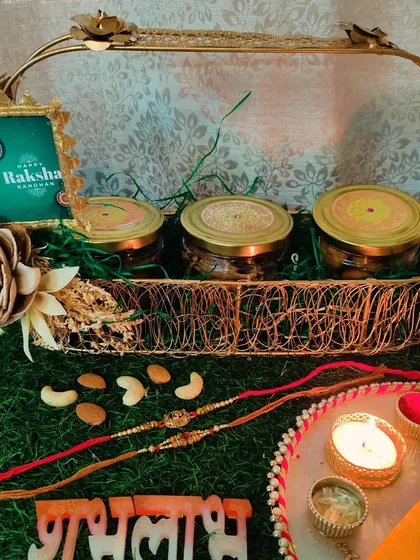 A beautiful Raksha Bandhan hamper designed to make the celebration complete. This premium golden tray holds three jars of my signature snacks: healthy Ragi Chips, traditional Khasta Kachori, and jaggery Ragi Cookies, accompanied by rakhis and a pooja thali.