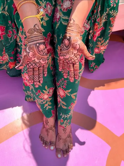 A beautiful shot of coordinated hand and feet mehendi. The designs feature lotus and peacock elements, creating a cohesive and artistic look.