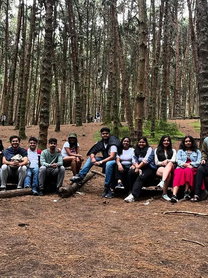 The whole group relaxing on logs in the pine forest, a classic Kodaikanal experience.