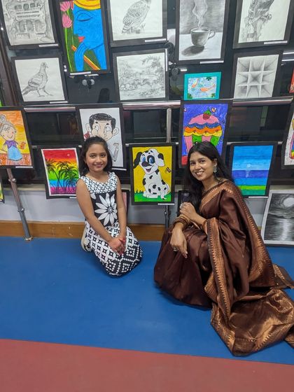 A proud moment for a student and her teacher, sitting amongst the gallery of impressive artworks. This captures the supportive relationship that is central to our teaching philosophy.