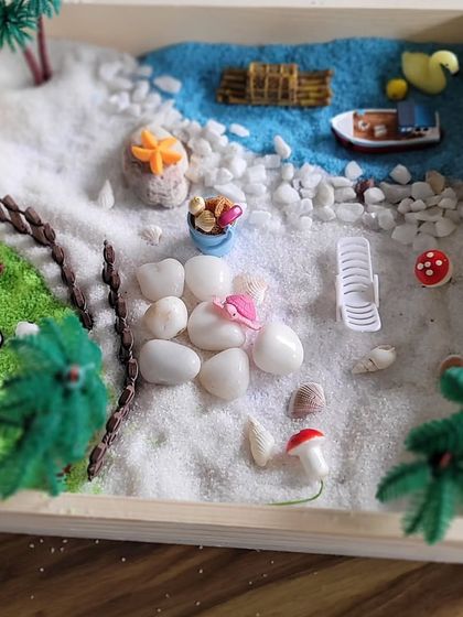This Zen garden creation showcases a serene beach with white sand, blue water, and a small boat. These workshops are a wonderful way for kids to practice meditation through art.