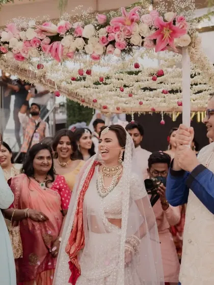 A joyous bridal entry under a beautiful 'phoolon ki chadar' held by her loved ones. We coordinate these traditions to be seamless and full of emotion.