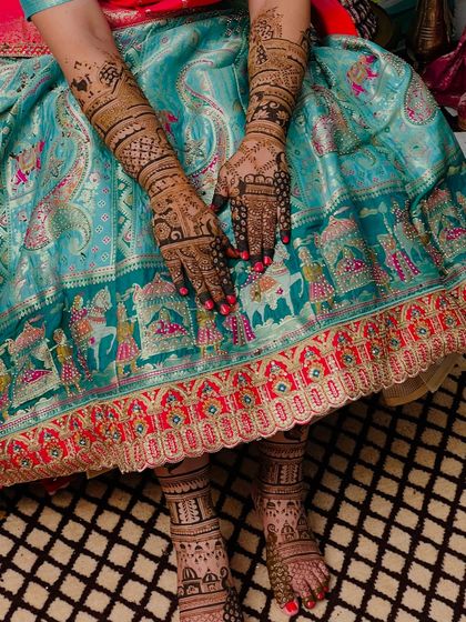 A complete bridal look, showing the coordination between the intricate hand mehendi and the beautiful foot design.