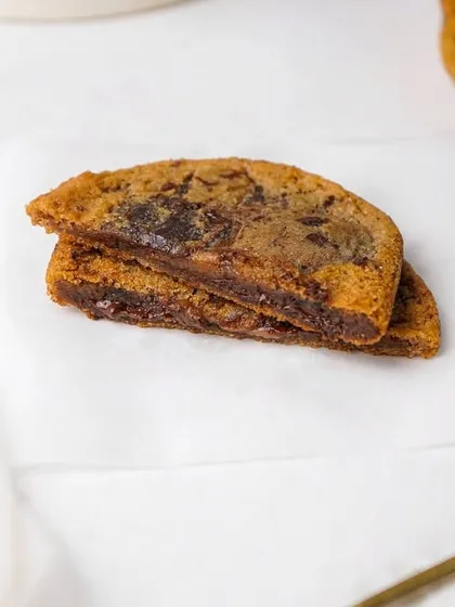 A chocolate chip cookie cut in half to show the soft, chewy center and melted chocolate chunks. This detailed shot is designed to make mouths water.