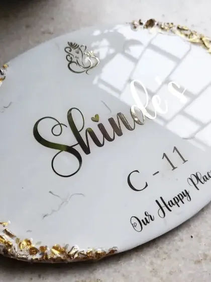 "Our Happy Place." This oval resin nameplate for the Shinde family has a clean white marble look with a sparkling gold geode edge, creating a simple yet beautiful statement for their home.