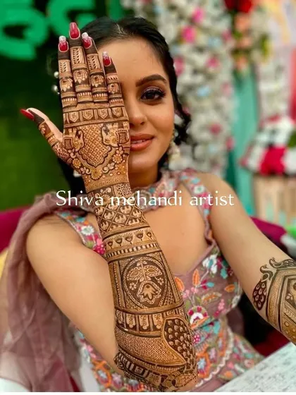 A happy client showing off her intricate mehendi, which features a mix of traditional patterns and peacock motifs.