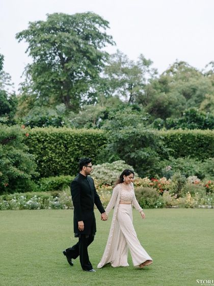 A couple takes a romantic stroll through a beautifully manicured garden. The image feels serene and timeless, showcasing their connection in a peaceful, green space.