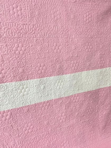 A close-up of the intricate quilting on the back of the pink hexagon quilt.