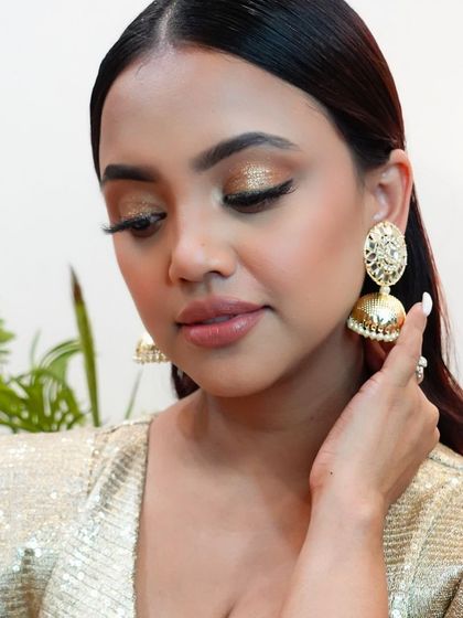 A detailed shot of the bronzy glitter eyeshadow. The texture and shine of the glitter add a luxurious feel to the overall look.