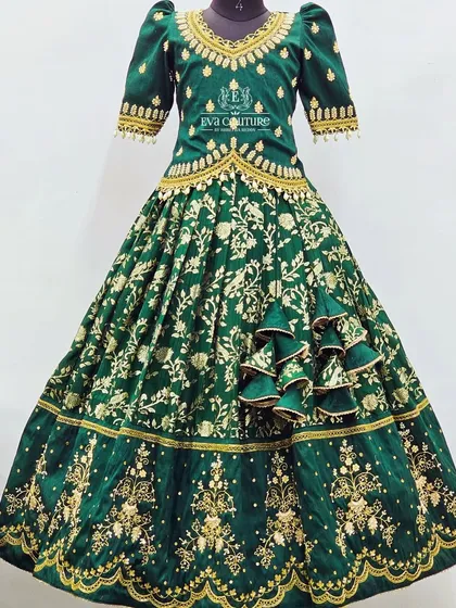For a truly grand occasion, this emerald green velvet lehenga is a showstopper. The entire set is covered in heavy gold maggam work, from the detailed blouse to the borders of the full-flared skirt, creating a regal look for your little one.