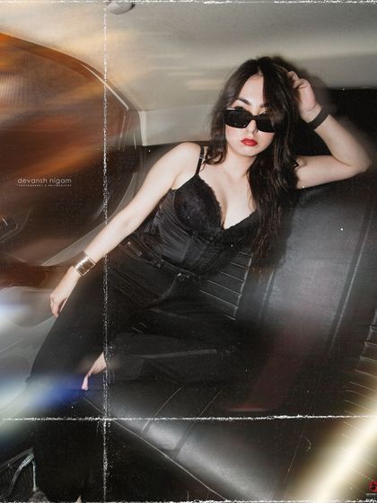 A classic cool-girl pose in the backseat, showing off the all-black outfit and sunglasses.