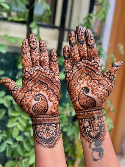 The back of the hands, featuring a beautiful peacock design that complements her panda tattoo.