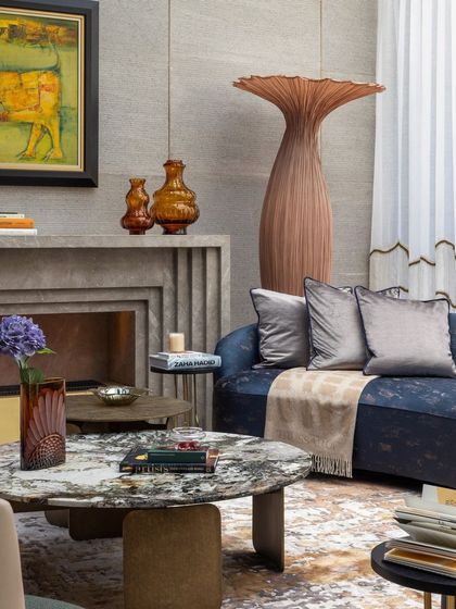 A close-up of the curated decor in the living room, showing a mix of materials like stone, metal, and fabric. The custom marble coffee table and unique floor vase add artistic flair to the space.