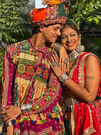 A candid moment of joy. This couple is all smiles in their vibrant, coordinated Garba outfits, ready to take on the dance floor together.