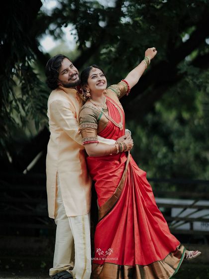 A playful and romantic shot of the couple, the bride pointing upwards with a smile as her groom holds her close.