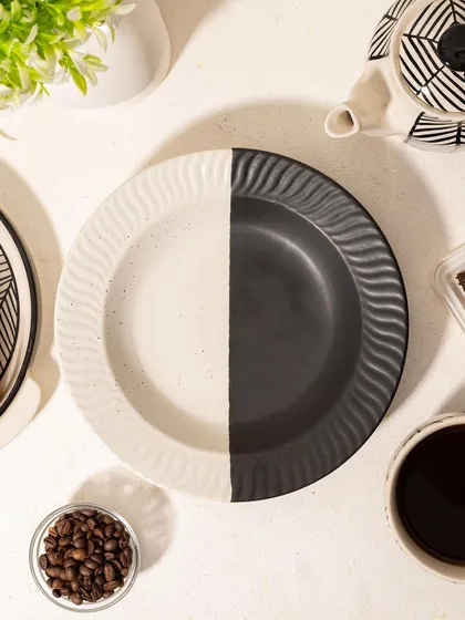 A top-down shot of an empty black-and-white plate from Homesmith, styled with coffee and coffee beans. This sets a scene and creates anticipation.