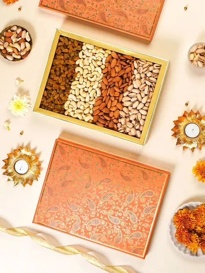 A beautiful flatlay of a festive dry fruit gift box with paisley designs. The minimal styling with diyas and a gold ribbon creates an elegant and traditional feel for Diwali gifting.