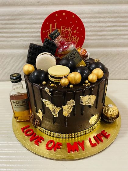 A decadent chocolate cake for the "love of my life," featuring a dark chocolate drip, gold leaf, macarons, and miniature bottles of Teacher's whiskey.