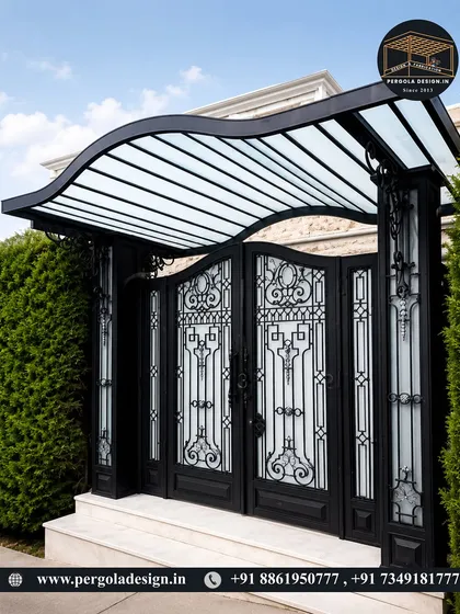 A beautiful entrance featuring a curved glass and steel canopy over an ornate gate. The wave-like design of the canopy adds a unique, modern touch to the traditional metalwork.