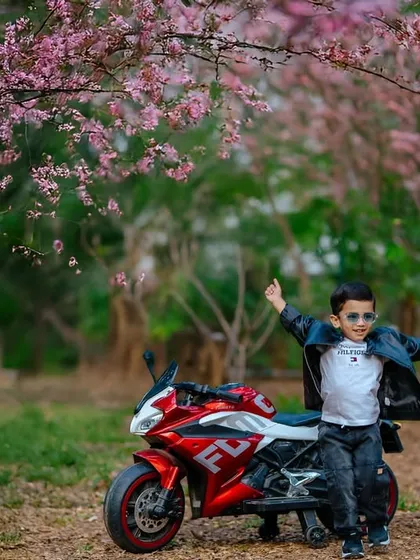Capturing the adventurous spirit of a toddler is pure joy. This outdoor portrait session uses a fun toy motorcycle prop and the beautiful backdrop of spring blossoms to tell a story of childhood freedom and play.