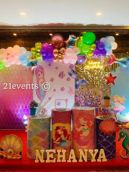 An enchanting mermaid theme for a magical under-the-sea party. This setup includes character backdrops, a sequin panel, themed pedestals, and a vibrant balloon garland with chrome and pastel colors.