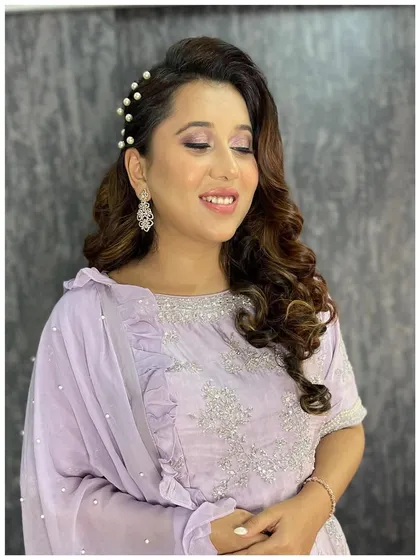 A close-up of the pearl-accented hairstyle. The soft curls are swept to one side and decorated with elegant pearl pins for a touch of classic charm.