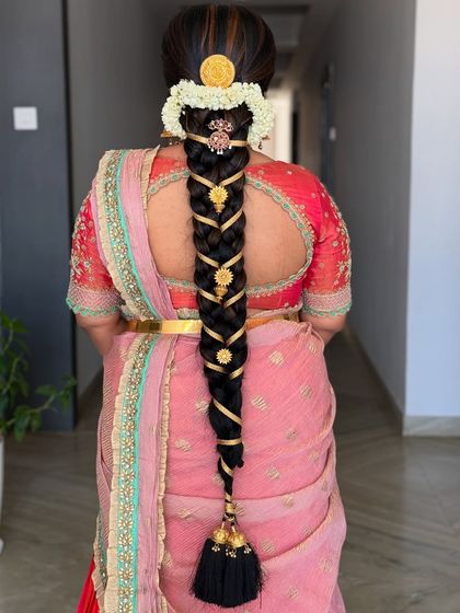 An intricate and traditional South Indian braid, woven with gold ribbons and adorned with classic temple-style hair jewelry.