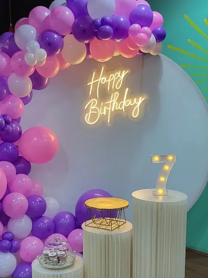A close-up of the 7th birthday balloon arch and neon sign.