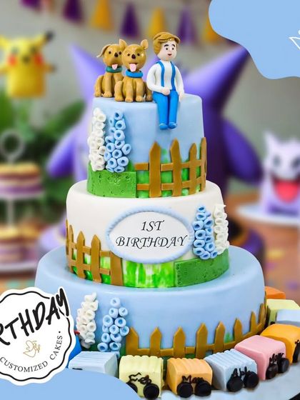 A grand three-tier cake for a first birthday. This impressive creation features a train, a teddy bear, and a fence design, perfect for a big celebration.