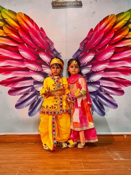 Our little Krishna and Radha posing in front of the studio's iconic wings mural during our Janmashtami celebration.
