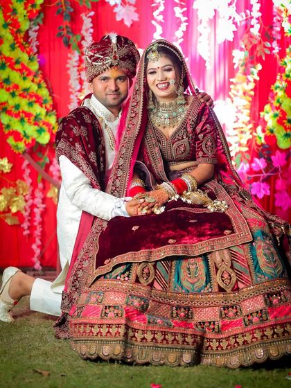A traditional seated portrait of the wedding couple against a vibrant floral backdrop.